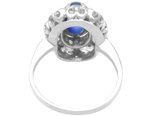 fig 6. An antique 14ct white gold ring featuring an oval cabochon blue sapphire surrounded by a halo of round diamonds.