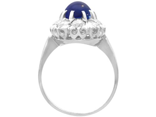 fig 7. An antique 14ct white gold ring featuring an oval cabochon blue sapphire surrounded by a halo of round diamonds.