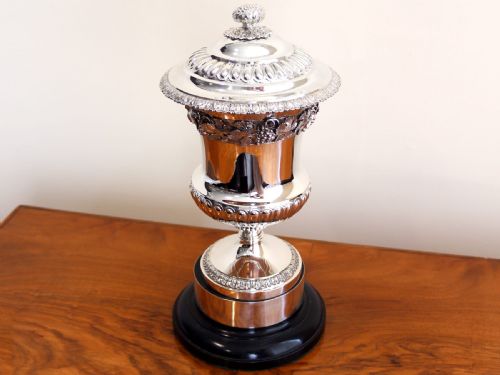 fig 2. A Victorian sterling silver presentation cup and cover decorated with a grape leaf band, resting on a round ebonised wood plinth.