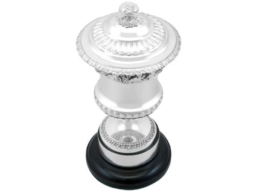 fig 3. A Victorian sterling silver presentation cup and cover decorated with a grape leaf band, resting on a round ebonised wood plinth.