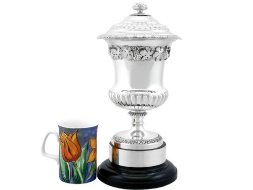 fig 4. A Victorian sterling silver presentation cup and cover decorated with a grape leaf band, resting on a round ebonised wood plinth.
