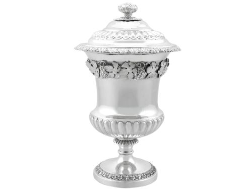 fig 6. A Victorian sterling silver presentation cup and cover decorated with a grape leaf band, resting on a round ebonised wood plinth.