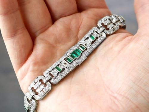 fig 2. An Art Deco platinum strap bracelet featuring geometric links set with diamonds and green accent emeralds.