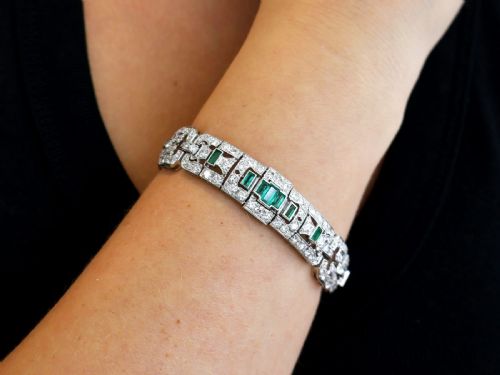 fig 3. An Art Deco platinum strap bracelet featuring geometric links set with diamonds and green accent emeralds.