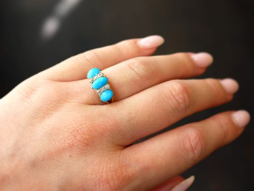 fig 4. A late Victorian 15ct yellow gold ring featuring three oval turquoise cabochons separated by small diamond accents.