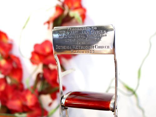 fig 1. A miniature sterling silver folding chair with brown enamel seat and backrest panels mounted on a black rectangular base.