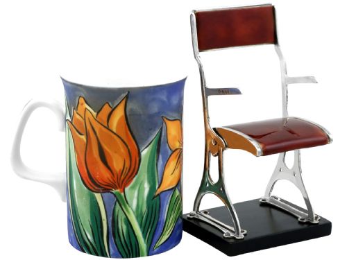 fig 3. A miniature sterling silver folding chair with brown enamel seat and backrest panels mounted on a black rectangular base.
