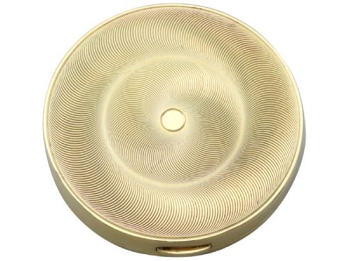 fig 1. A circular 9ct yellow gold powder compact featuring an engine-turned swirling pattern and a central ruby and diamond cluster.