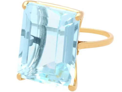 fig 3. A substantial rectangular emerald-cut light blue aquamarine gemstone secured in a four-claw 18ct yellow gold ring mounting.
