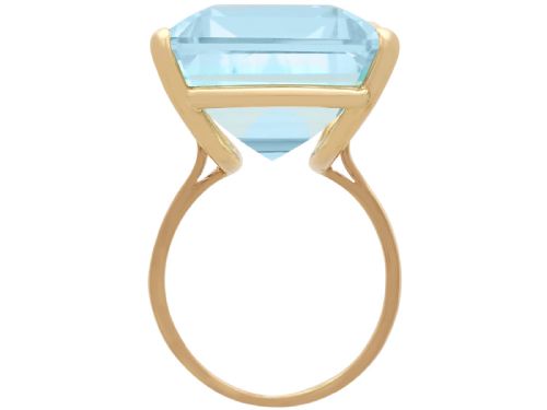 fig 5. A substantial rectangular emerald-cut light blue aquamarine gemstone secured in a four-claw 18ct yellow gold ring mounting.