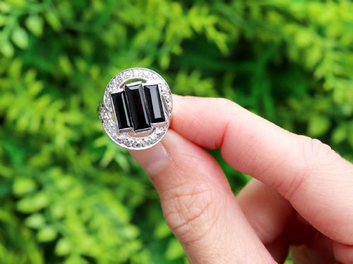 fig 1. An Art Deco style platinum dress ring displaying three vertical rectangular black onyx plaques enclosed within a circular diamond-set halo frame.