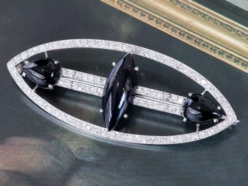 fig 3. An Art Deco platinum brooch featuring an openwork navette frame set with diamonds and three carved black onyx stones.
