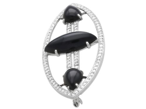 fig 4. An Art Deco platinum brooch featuring an openwork navette frame set with diamonds and three carved black onyx stones.