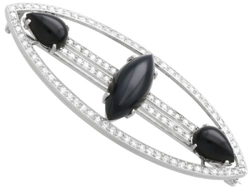 fig 5. An Art Deco platinum brooch featuring an openwork navette frame set with diamonds and three carved black onyx stones.