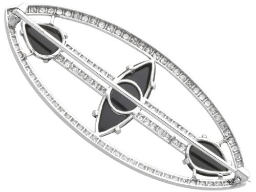 fig 6. An Art Deco platinum brooch featuring an openwork navette frame set with diamonds and three carved black onyx stones.