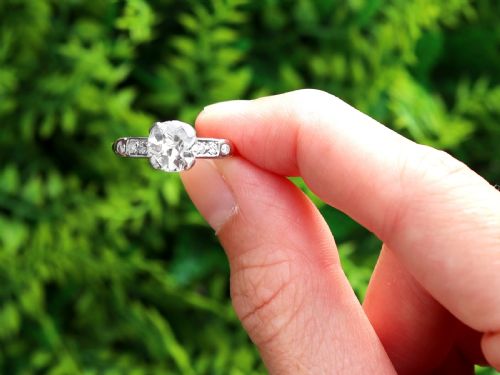 fig 1. A round central diamond solitaire ring in a platinum claw setting with diamond-set shoulders on a 14ct yellow gold band.
