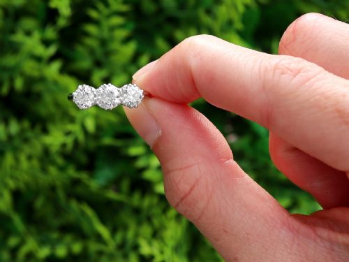 fig 1. A platinum trilogy ring featuring three round brilliant diamonds set in individual claw mounts along a slender polished band stamped PLAT.