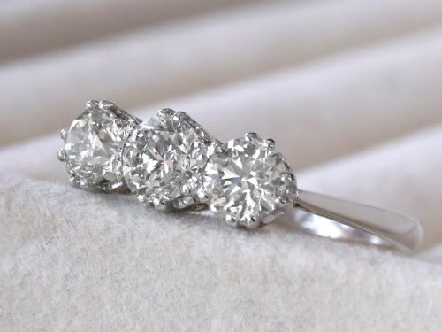 fig 2. A platinum trilogy ring featuring three round brilliant diamonds set in individual claw mounts along a slender polished band stamped PLAT.