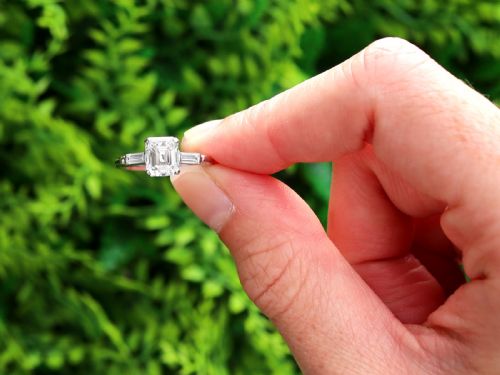 fig 1. A platinum solitaire ring featuring a central square step-cut diamond flanked by two baguette diamonds on a plain band.