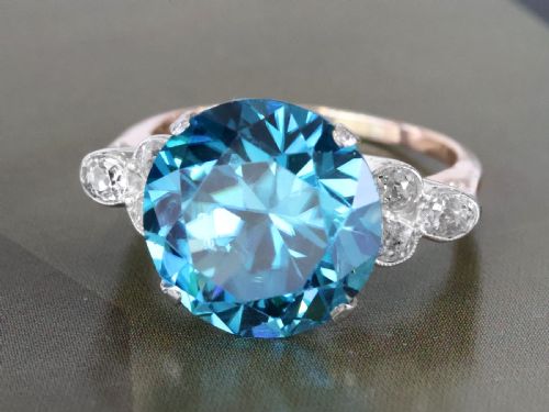 fig 3. An Art Deco 9ct yellow gold ring featuring a large round-cut blue zircon flanked by diamond-set shoulders.