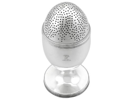 fig 1. An egg-shaped George III sterling silver condiment caster featuring a perforated upper section, reeded borders, a small engraved crest, and a pedestal foot.