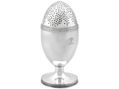 fig 2. An egg-shaped George III sterling silver condiment caster featuring a perforated upper section, reeded borders, a small engraved crest, and a pedestal foot.