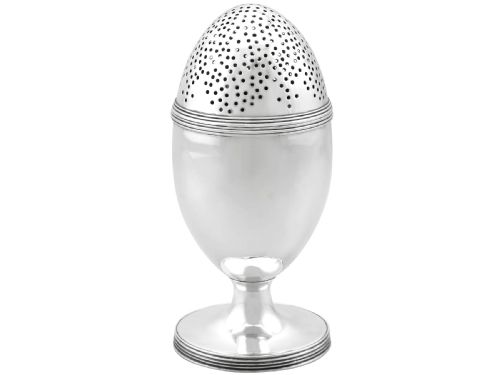 fig 3. An egg-shaped George III sterling silver condiment caster featuring a perforated upper section, reeded borders, a small engraved crest, and a pedestal foot.