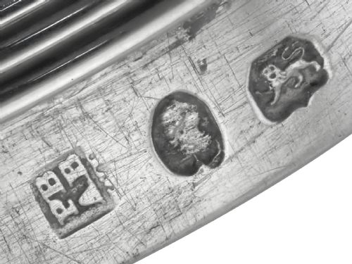 fig 7. An egg-shaped George III sterling silver condiment caster featuring a perforated upper section, reeded borders, a small engraved crest, and a pedestal foot.