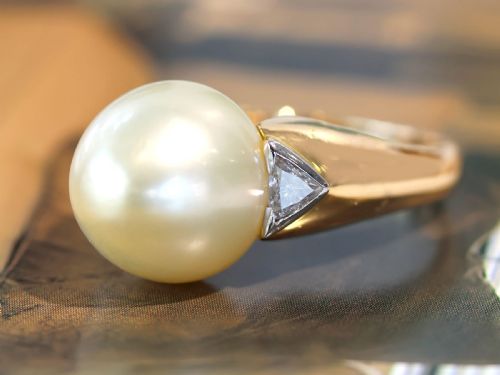 fig 4. A vintage 18ct yellow gold ring featuring a central round cream cultured pearl flanked by two triangular diamonds.