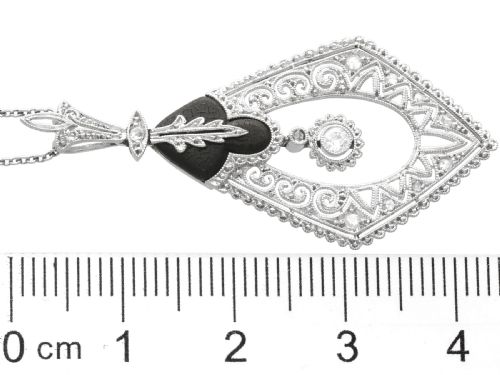 fig 7. A diamond-shaped Art Deco platinum filigree pendant set with carved black onyx and a central suspended diamond drop.