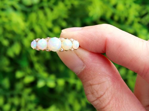 fig 1. An Edwardian 18ct yellow gold five stone ring featuring graduated cabochon white opals with small diamond accents and full interior British hallmarks.