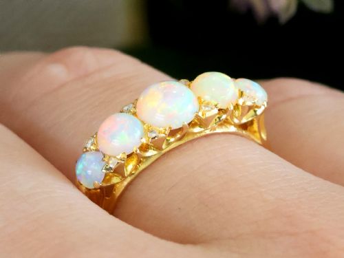 fig 3. An Edwardian 18ct yellow gold five stone ring featuring graduated cabochon white opals with small diamond accents and full interior British hallmarks.
