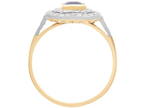 fig 7. An 18ct yellow gold ring featuring a central emerald-cut blue sapphire framed by a geometric double halo of round diamonds with millegrain edging.