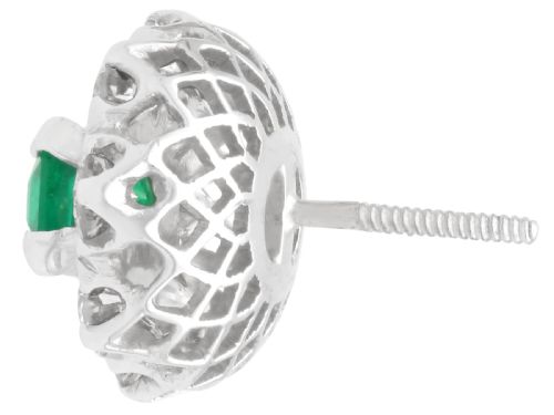 fig 6. A pair of 18ct white gold cluster earrings featuring central emerald-cut green emeralds surrounded by a halo of round brilliant diamonds.