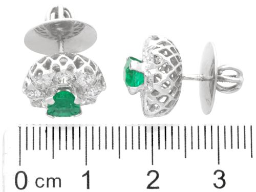 fig 7. A pair of 18ct white gold cluster earrings featuring central emerald-cut green emeralds surrounded by a halo of round brilliant diamonds.
