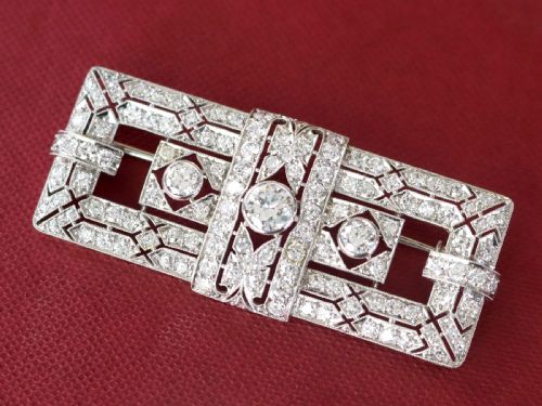 fig 3. A rectangular Art Deco platinum brooch featuring intricate geometric openwork millegrain setting filled with round diamonds surrounding a central bezel-set diamond.