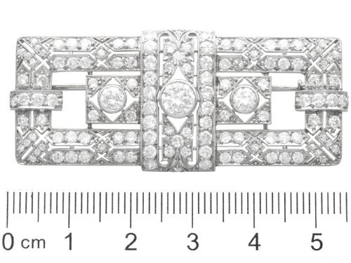 fig 8. A rectangular Art Deco platinum brooch featuring intricate geometric openwork millegrain setting filled with round diamonds surrounding a central bezel-set diamond.