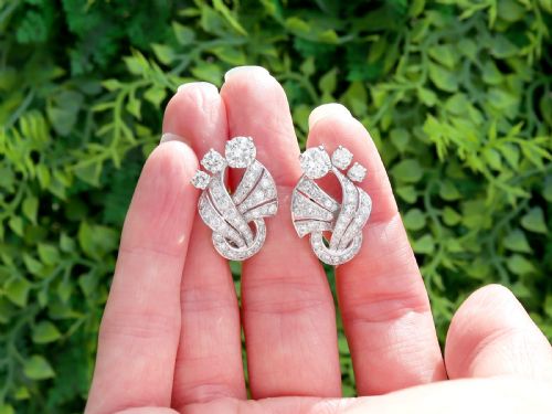 fig 1. A pair of platinum earrings crafted in a sweeping fan and scroll design, fully set with brilliant-cut diamonds.