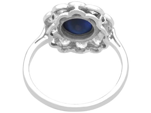 fig 6. A platinum ring set with a central round cabochon blue sapphire surrounded by a halo of ten round diamonds.