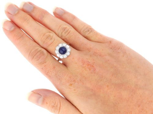 fig 8. A platinum ring set with a central round cabochon blue sapphire surrounded by a halo of ten round diamonds.