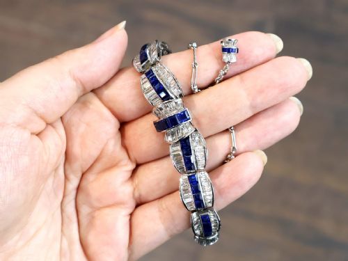 fig 3. An Art Deco platinum collar necklace set with central square-cut blue sapphires bordered by baguette and round diamonds.