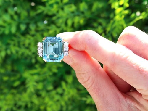 fig 1. A 14ct yellow gold dress ring featuring a large emerald-cut light blue aquamarine central gemstone flanked by six round diamonds.