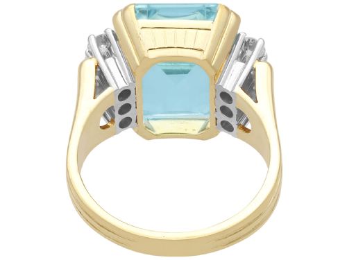 fig 5. A 14ct yellow gold dress ring featuring a large emerald-cut light blue aquamarine central gemstone flanked by six round diamonds.