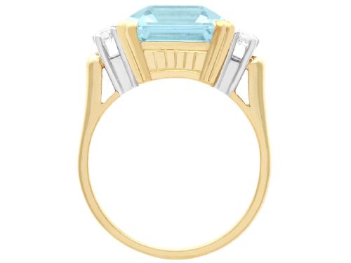 fig 6. A 14ct yellow gold dress ring featuring a large emerald-cut light blue aquamarine central gemstone flanked by six round diamonds.