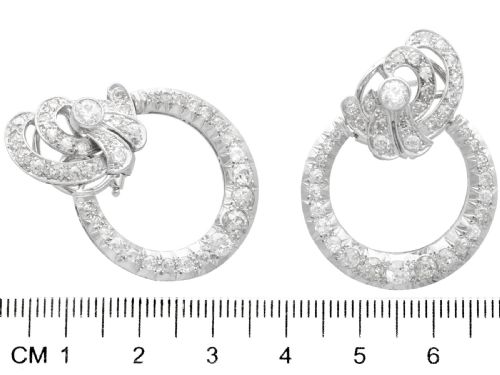 fig 4. Pair of platinum clip-on earrings featuring circular diamond-set lower hoops suspended from geometric diamond scroll tops.