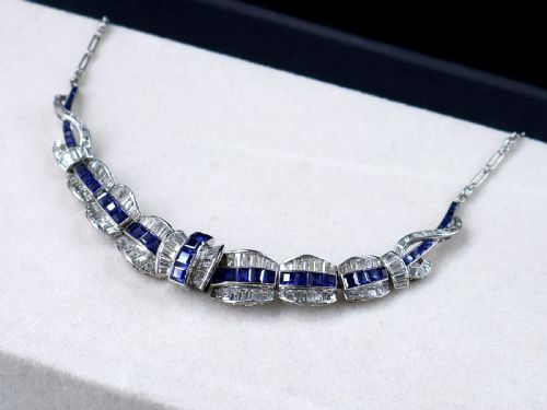 fig 6. An Art Deco platinum collar necklace set with central square-cut blue sapphires bordered by baguette and round diamonds.