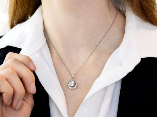 fig 3. An antique platinum halo pendant featuring a central round diamond surrounded by a scalloped border of smaller diamonds on a fine chain.