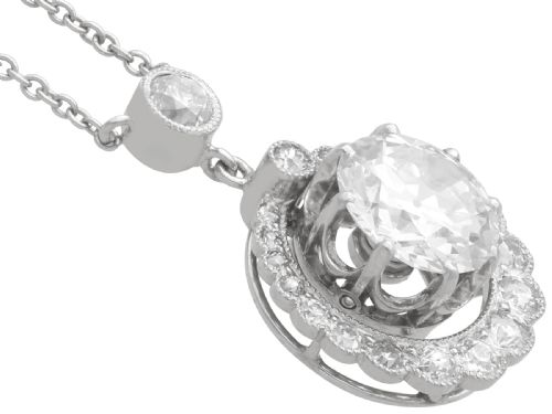 fig 7. An antique platinum halo pendant featuring a central round diamond surrounded by a scalloped border of smaller diamonds on a fine chain.