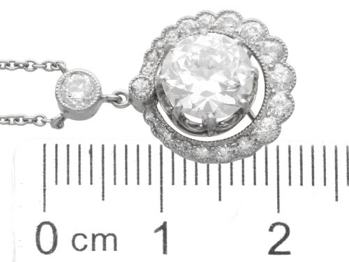 fig 9. An antique platinum halo pendant featuring a central round diamond surrounded by a scalloped border of smaller diamonds on a fine chain.
