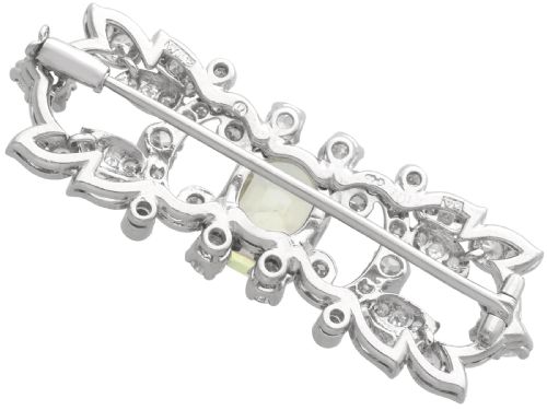 fig 7. An Art Deco platinum brooch centered with an oval cushion-cut yellow sapphire enclosed by diamond-set scrollwork and foliate motifs.